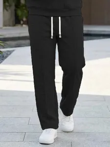 Close-up detail view of men's black waffle knit pants featuring a white drawstring waist