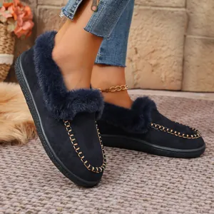 Close-up of navy blue suede winter loafers with faux fur trim and gold stitching.