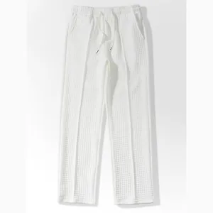 Detail view of the soft waffle texture on white men's casual loose-fit trousers
