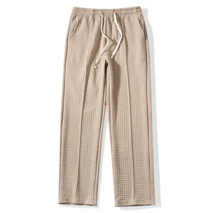 Detailed close-up of beige waffle knit casual pants with elastic drawstring waist.