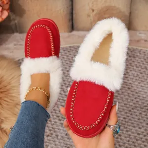 Close-up of red suede winter slippers with white faux fur lining and warm flat sole.