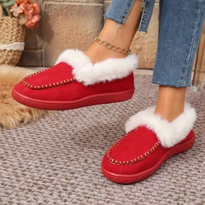 Close-up of cozy red suede slippers with white faux fur lining and gold chain detail
