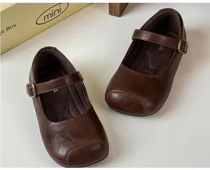 Nahaufnahme von braunen Mary Jane Lederschuhen im Vintage-Stil für Mädchen mit Metallschnallen