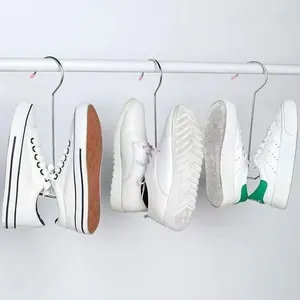 Ganci in acciaio inossidabile per asciugare scarpe e sneakers bianche su barra bianca