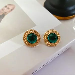 Vue détaillée de boucles d'oreilles vintage en or avec des pierres vert émeraude rondes