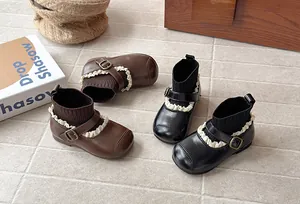 Retro girls' stretch sock boots with ruffle trim and buckle detail on stone floor.
