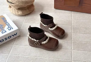 High-angle detail view of retro brown children's sock boots with lace and buckle accents