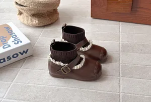 Close-up of vintage brown girls' sock boots with lace trim and buckle strap details.