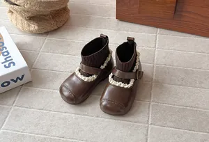 Close-up of retro brown girl's sock boots with delicate lace trim and buckle detail.