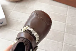 Close-up of vintage brown girls' sock boots with delicate lace trim and round toe design