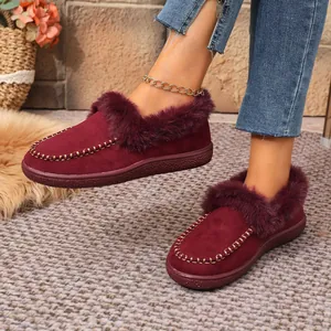 Close-up of burgundy suede winter shoes with plush fur trim and golden chain stitching