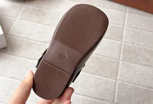 Close-up of the non-slip brown rubber sole of children's boots showing size 23.