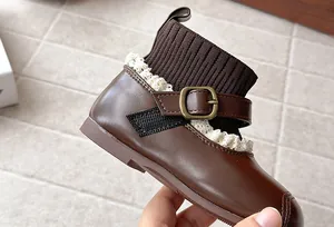 Close-up detail of girls brown leather sock boot with lace trim and metallic buckle