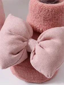 Detalle macro de un calcetín de punto rosa para bebé con lazo decorativo grande.
