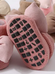 Primer plano calcetines bebé rosa con suela antideslizante y detalle de lazo decorativo