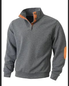 Vista de detalle: sudadera gris acolchada con parches y forro del cuello naranja.