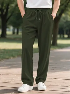 Men's olive green corduroy casual pants with drawstring waist shown in outdoor park