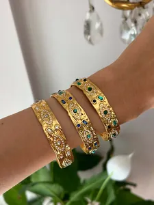 Close-up of gold stainless steel evil eye bangles with colorful stones on a wrist.