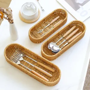 Oval woven cutlery storage basket for kitchen forks and spoons on marble table.