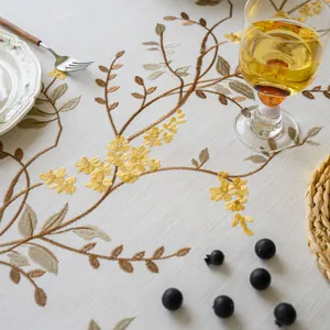 Detailed close-up of elegant floral embroidery on a premium linen-style beige tablecloth.