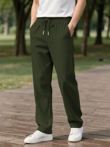 Detail of men's dark green corduroy casual pants with drawstring waist in a park setting.