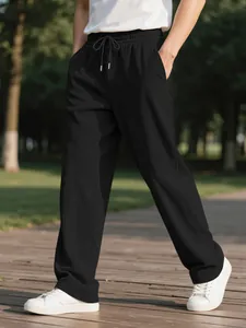 Detailed shot of men's black corduroy casual pants shown in a natural outdoor park setting