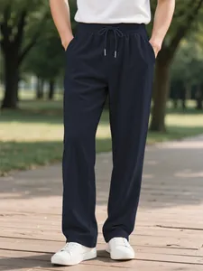 Close-up of men's navy blue corduroy pants with drawstring waist and straight fit.