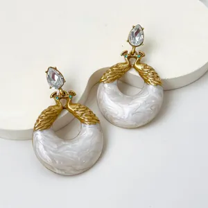 Detalle de pendientes vintage de pavo real en resina con toques dorados y acabado jaspeado.