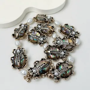 Collana vintage con scarabei iridescenti e perle, finitura oro antico.
