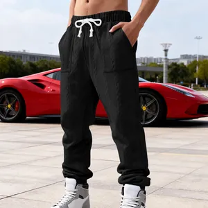 Detail view of men's black jacquard sweatpants with textured fabric and white drawstring.
