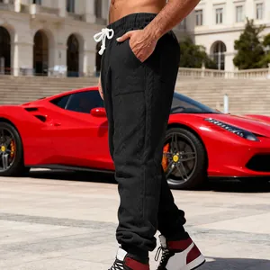 Close-up detail of men's black heavy jacquard sweatpants with tapered cuffs and loose fit.