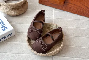 Detailed view of brown suede girl's princess shoes with lovely bows in a woven basket