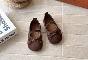 Detailed macro view of brown suede girls' Mary Jane flats with a decorative bow accent