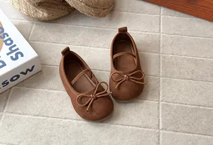 Detail of brown suede girl's ballet flats with elegant bow decoration and soft soles.