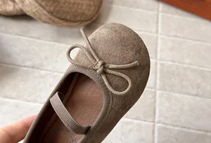Detail of suede girl's princess shoe with decorative bow and elastic strap