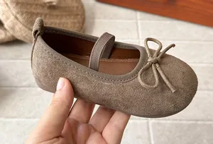 Close-up of brown suede girls Mary Janes with bow detail and elastic strap.