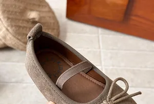 Detailed view of brown suede girls flat shoes with bow and elastic strap closure