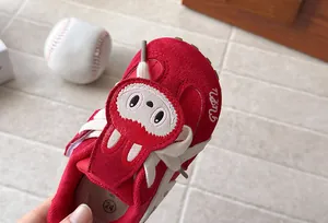 Detail of red children's sneaker featuring a cute monster patch and white laces
