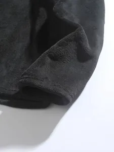 Dettaglio macro del morbido tessuto in pile nero di una calda felpa invernale da uomo