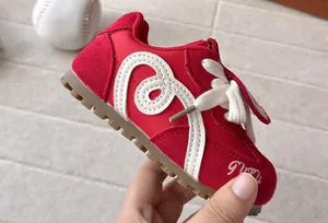 Close-up detail of red children's athletic sneakers with white decorative patterns