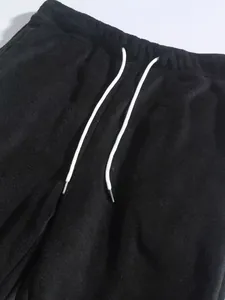 Detailopname van zwarte fleece joggingbroek met wit trekkoord
