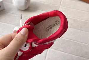 Close-up of breathable mesh lining and cushioned insole of children's red sneakers.