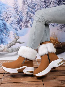 Detailed side view of brown suede snow boots with white faux fur trim and wedge sole