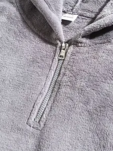 Dettaglio della mezza zip argentata e della morbida e calda texture in pile grigio.