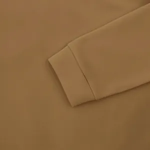 Detailed macro shot showing the ribbed cuff and heavy fleece fabric of the tan sweatshirt