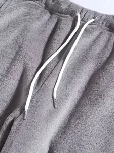 Detailopname van een grijze pluchen joggingbroek voor heren met trekkoord in de taille