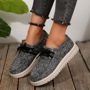 Detailweergave van grijze loafers van getextureerde stof met dikke witte zolen en veters
