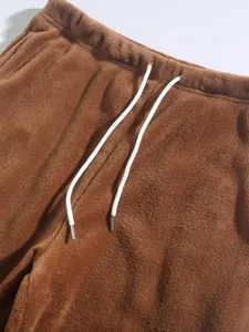 Close-up van een bruine pluchen joggingbroek met een elastische taille en trekkoord