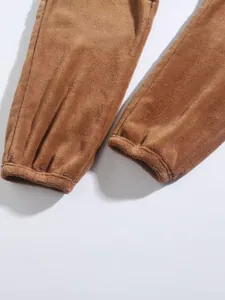 Detail van zachte fleece textuur en elastische manchetten van een bruine trainingsbroek