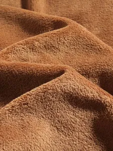 Primo piano di morbido tessuto pile marrone con spessa trama felpata per tuta invernale